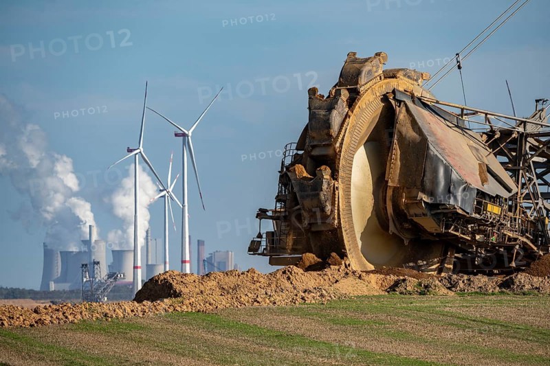 Opencast lignite mine Garzweiler II, bucket wheel excavator dredging, at the edge of the opencast mine near the village of Lützerath, belongs to Erkelenz in the district of Heinsberg, in the background wind farm, and the lignite-fired power plant Neurath, North Rhine-Westphalia, Germany