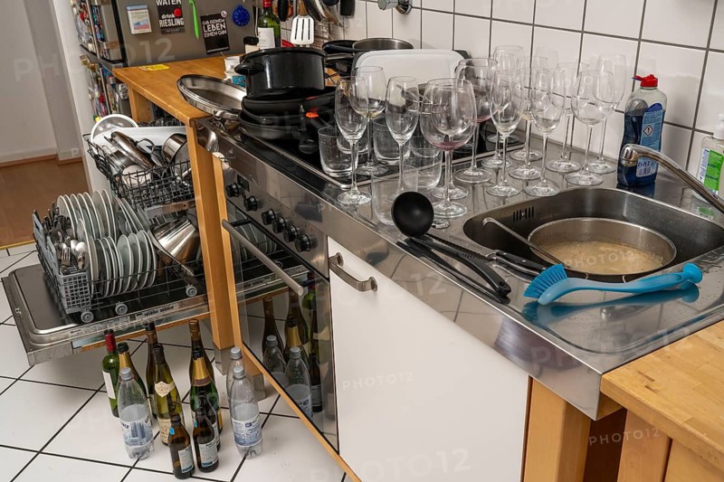 Kitchen after a big dinner, cooking party, dishwasher, full, with cleaned dishes, dirty glasses, pots, cooking utensils on the sink, waiting to be washed