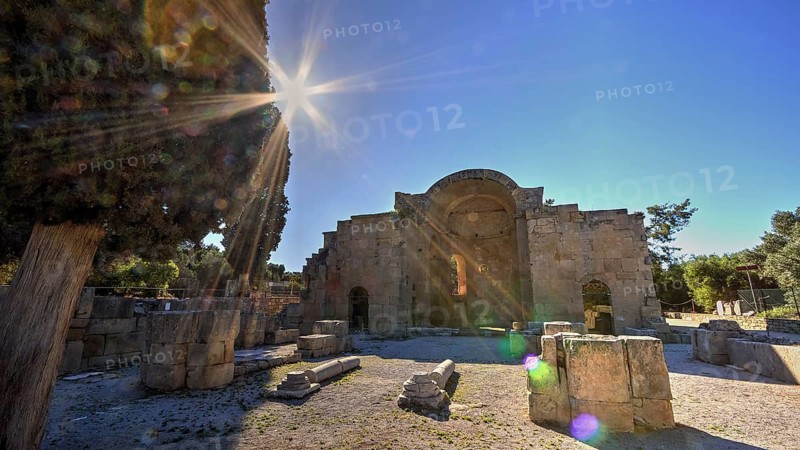 Titus Basilica, sun-drenched ancient ruin with tree in the foreground, blue sky and architectural details, Gortyn, Gortyna, Gortys, ancient city in central southern Crete, later capital of the Roman province of Creta, Crete, Greek Islands, Greece