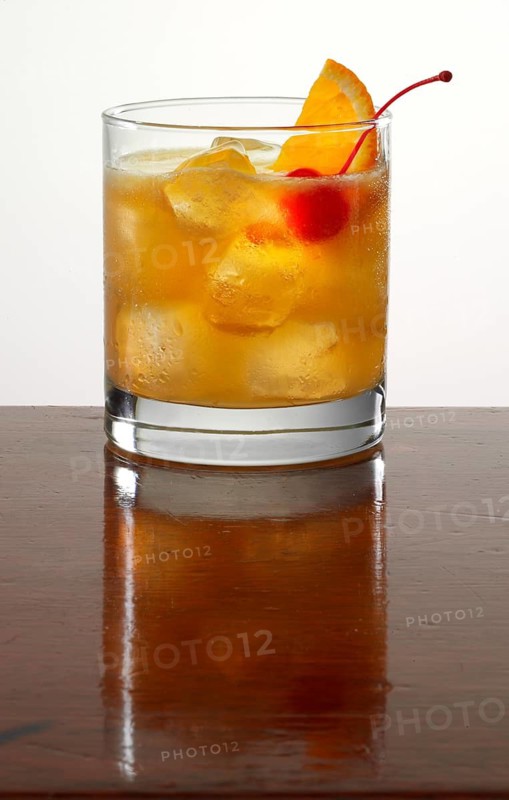 Cocktail on ice throws, cocktail cherry and orange wedge as garnish, studio recording