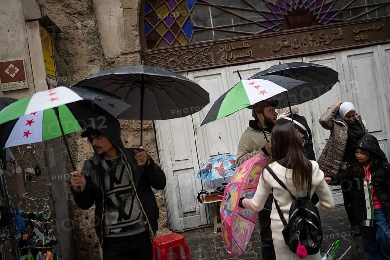 Damascus, Syria. December 6th 2025. Syrian street vendors selling umbrellas with the color of the Syrian revolutionary flag as the first rain of the winter falls after a year of drought, Damascus, Syria