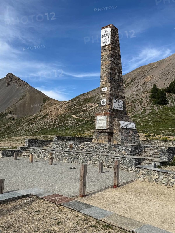 At Alpine pass Col de l'Izoard d'Izoard 2360 metres high road pass at pass summit of mountain road pass road 1934 erected altitude marker monument stele memorial column made of natural stone in memory of dedicated to General Baron Berge and workers of road construction, Cervières, Department Hautes-Alpes, Provence-Alpes-Cote d'Azur, France
