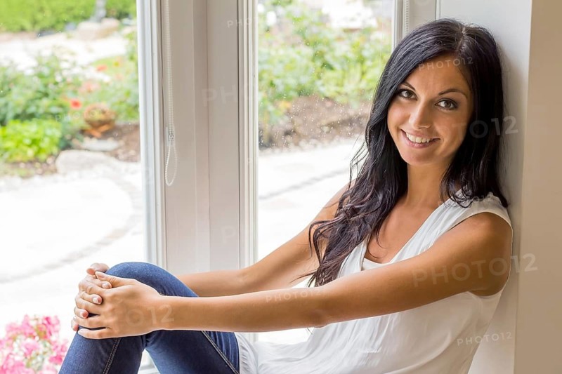 A young woman sits at the window and relaxes Studio shot, Vienna, Austria