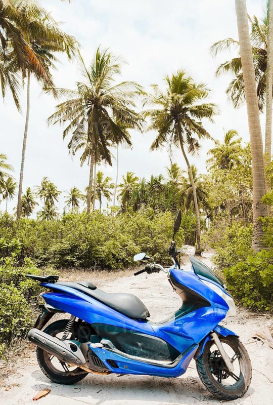 Bright blue typical common motor scooter parked on sandy dirt road. Transportation rentals in asia. Safety and and road trip concept. Travel like a local