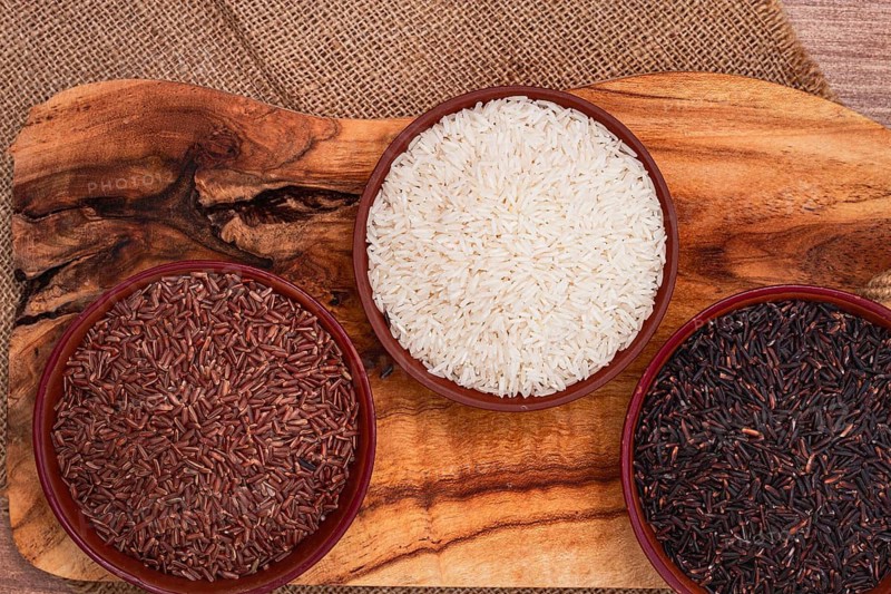 Set of red and black and white rice, in a bowl, on a wooden surface, rustic style, top view