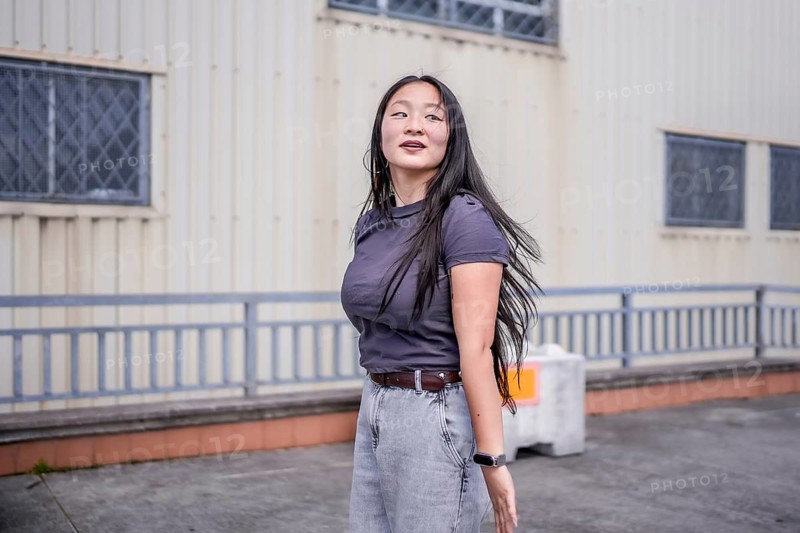 Three quarter length photo of a concentrated female asian young K-pop dancer performing a choreography outside an industrial building