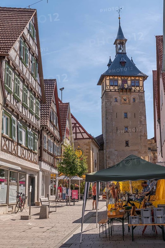 Marktstraße pedestrian zone in the city center with weekly market market and Upper Gate Tower, old town of Marbach am Neckar, historic buildings, half-timbered houses, market square, city history, cityscape, old town alleys, residential buildings, shops, alleyway view, half-timbered architecture, historic facades, regional cityscape, trade, shopping, market stand, retailer, marketplace, direct marketing, weekly market visitors, sales, stalls, Tower clock, Baden-Württemberg, Germany