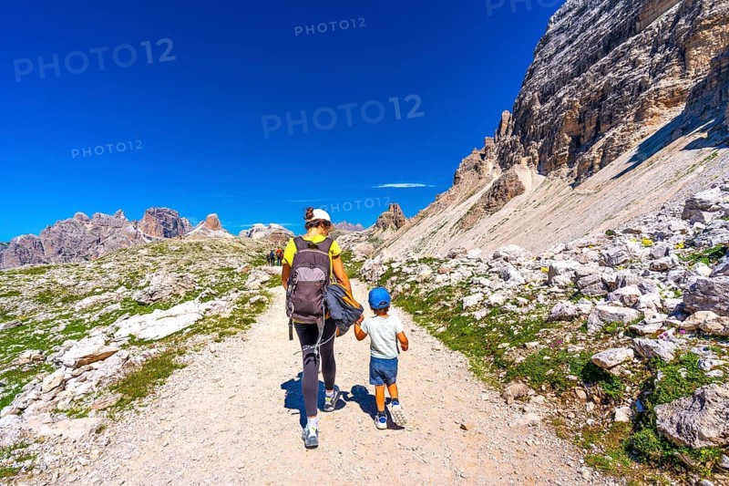 Mother and child enjoying a summer hike on a scenic trail amidst the breathtaking mountain landscape of tre cime di lavaredo in the dolomites, italy