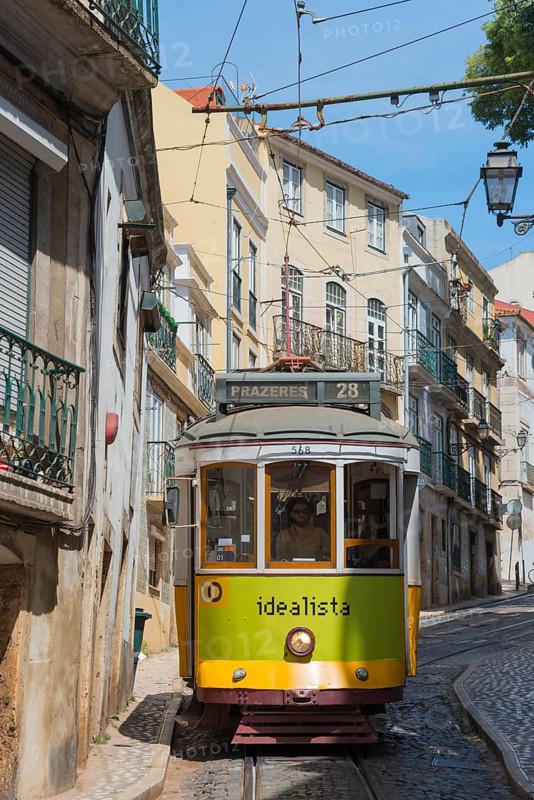 A yellow-green tram runs along a steep alley with old buildings in the background, Tram, Line 28, Carros eléctricos de Lisboa, Eléctricos de Lisboa, Old Town, Lisbon, Portugal