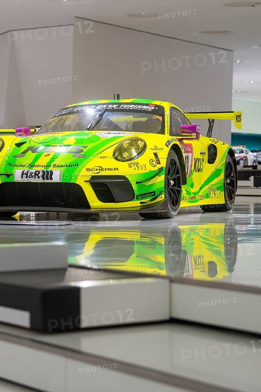 Yellow-green racing car in exhibition with shiny surface and reflection, Porsche Museum, Stuttgart, Germany