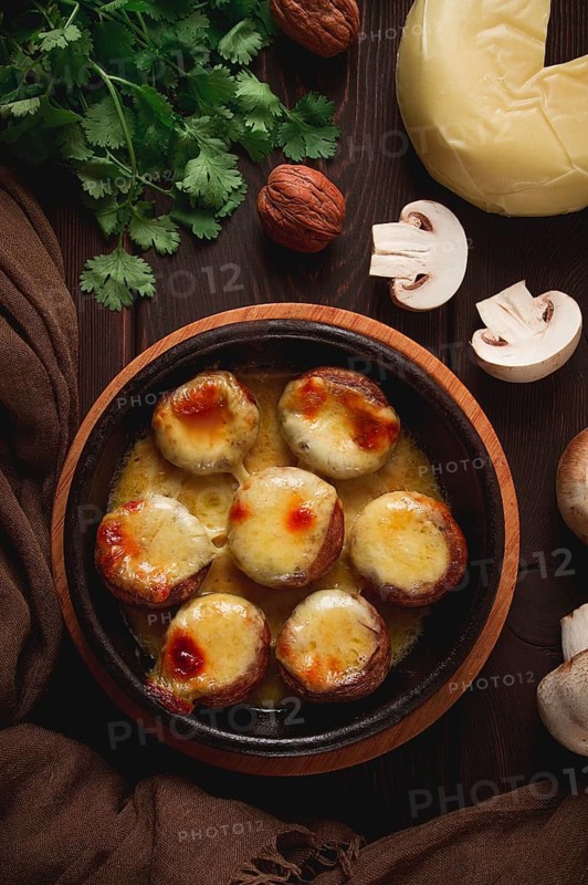 Traditional Georgian dish, appetizer, stuffed mushrooms, Sulguni cheese, baked in a Ketzi clay pan, on a wooden table, close-up, no people
