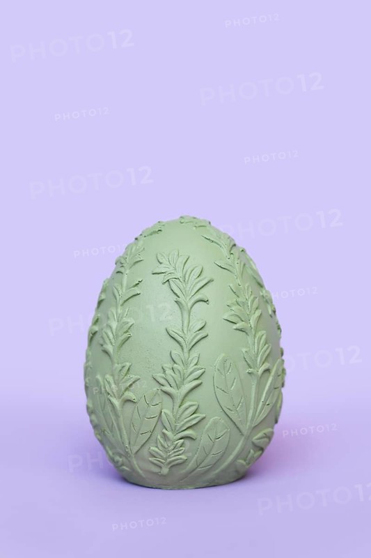 Single green Easter egg with leaf pattern on purple background