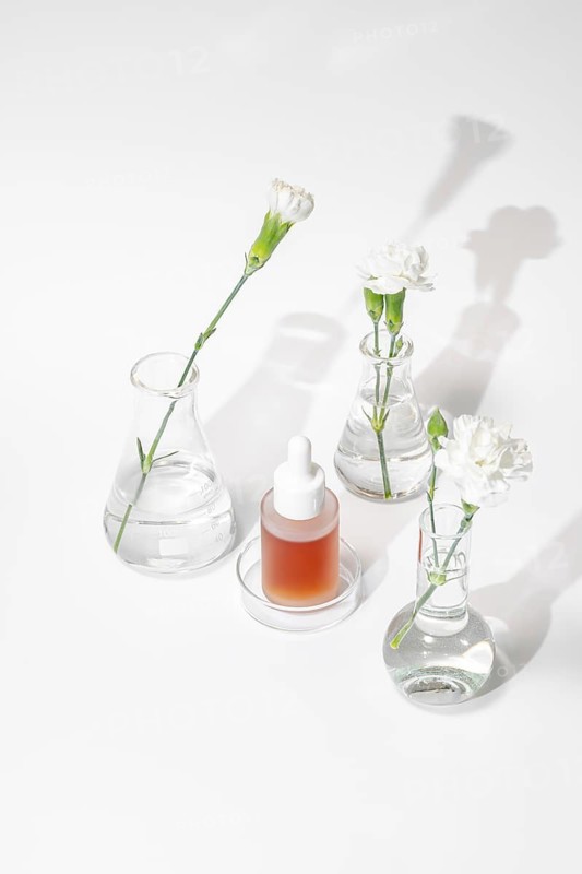 A serene setting of laboratory glassware featuring a skincare serum and fresh flowers, illustrating the blend of science and nature in skincare development