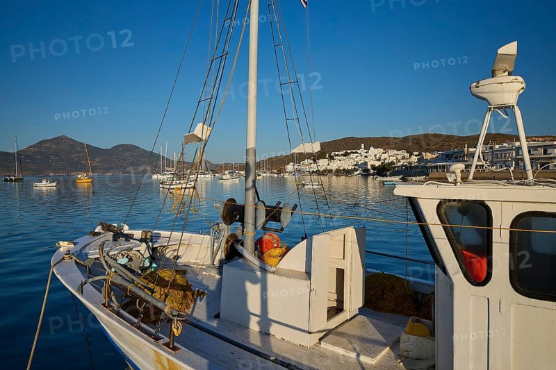 A sailboat in a quiet harbor with a view of white buildings and mountains in the background, Adamas, Adamantas, port town, volcanic island, island, Milos, Cyclades, Greek Islands, Greece