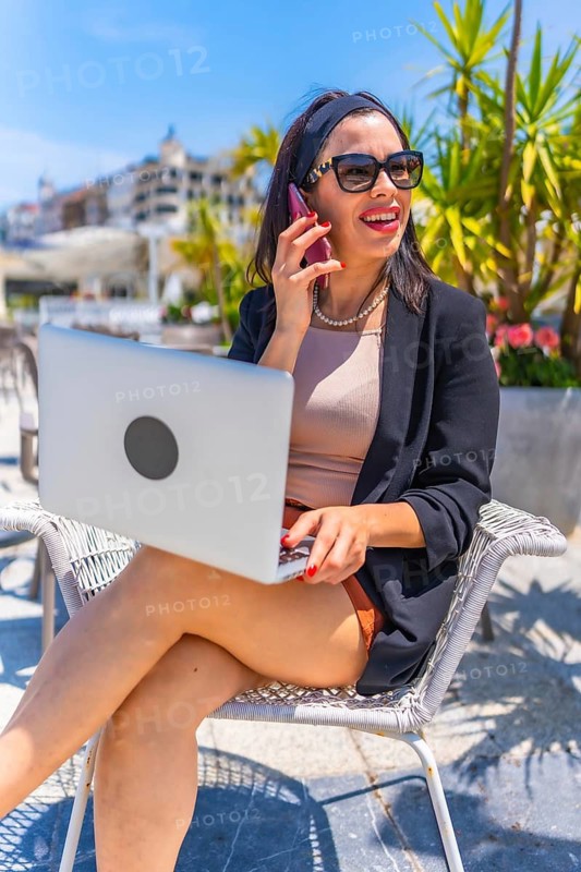 Vertical photo of an elegant busy businesswoman working in an outdoor city terrace
