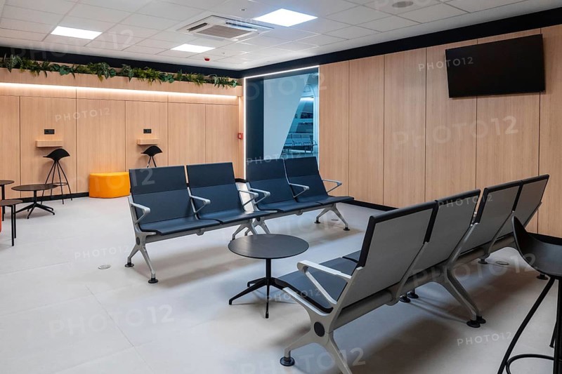Contemporary airport lounge providing a comfortable and productive workspace for travelers, featuring modern seating, tables, and a large screen display