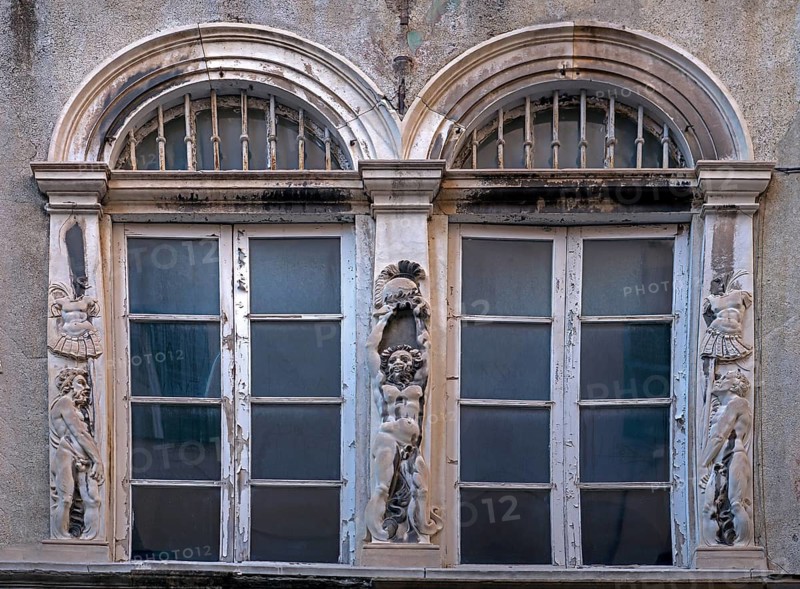 Historic arched windows framed with Roman relief motifs, old town centre in Genoa, Italy