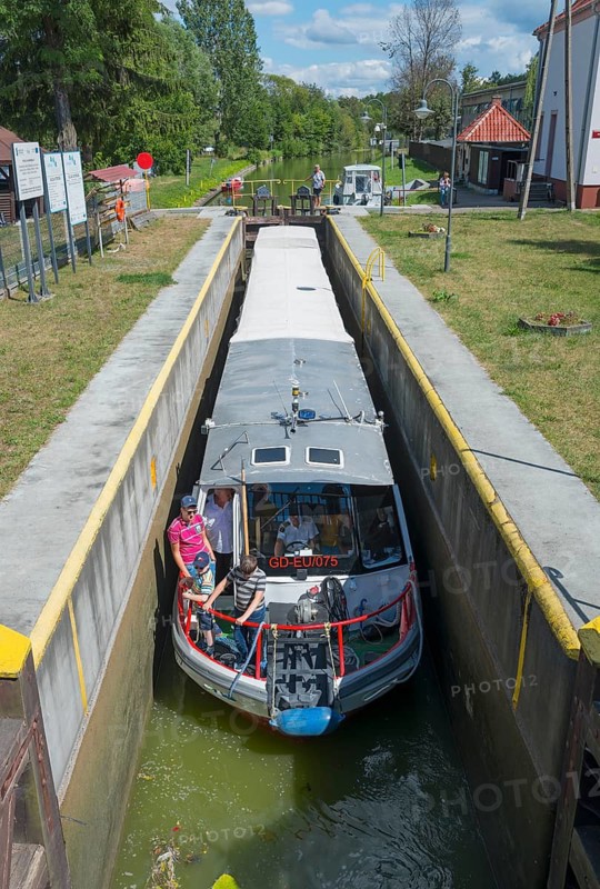 A boat in a lock on a canal on a sunny day, surrounded by green countryside, Ostroda, Upland Canal, Warminsko-Mazurskie, Warminsko-Mazurskie, Poland