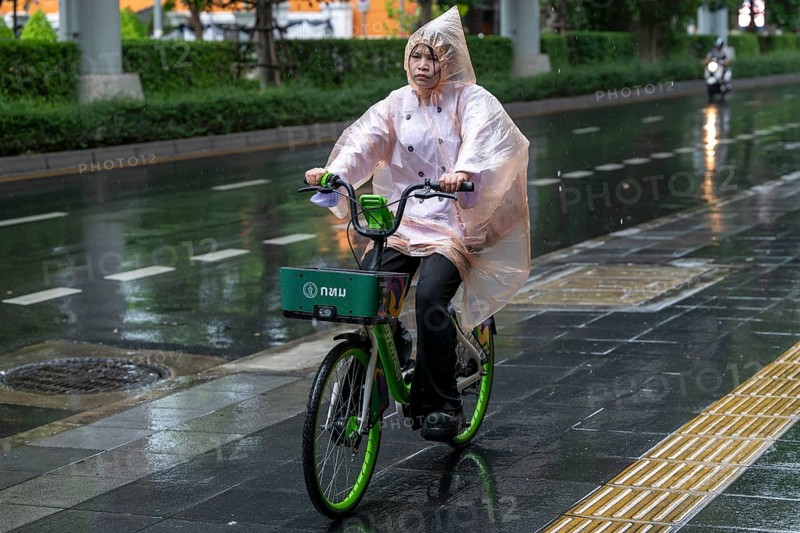 Female cyclist in rain, Bangkok, Thailand