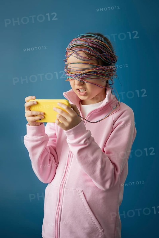 A child engrossed in a device, symbolizing the impact of the internet. Colorful cables wrap around his head, representing digital dependence and the influence of technology