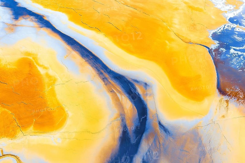 Stunning aerial photograph capturing a surreal abstract landscape with swirling patterns of rich yellow and deep blue