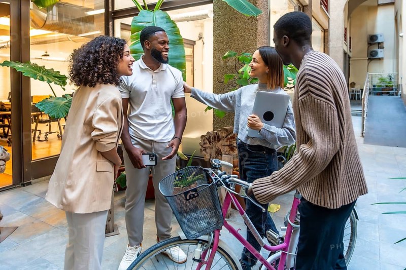 Cheerful and diverse colleagues talking at the entrance of a modern and sustainable coworking space