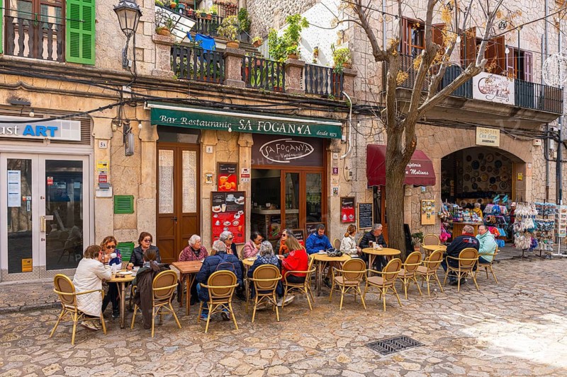 Tourists sit in a cafe in the picturesque mountain village of Valdemossa, Majorca, Balearic Islands, Spain