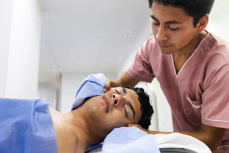 A physiotherapist provides a calming face massage to a patient in an Ecuadorian clinic. The setting highlights a professional and soothing healthcare environment
