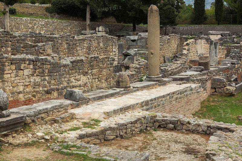 Old grey stone and red brick wall structures and columns at ancient 3rd century Roman ruins of Salona near Solin in late summer, Croatia