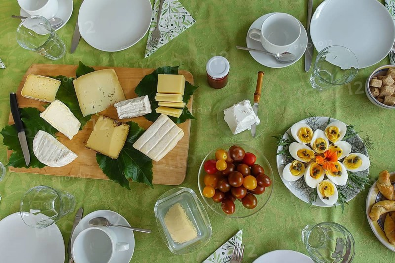 Breakfast table, breakfast, cold buffet, tomatoes in glass bowl, cheese board, wooden board, sliced eggs, hard eggs with capers on plate, dill, rocket, rocket, decoration, flower nasturtium, ham croissant, crockery, plates, cups, cutlery, glasses, butter plate, butter dish, jam in glass, food, food and drink, studio, Germany