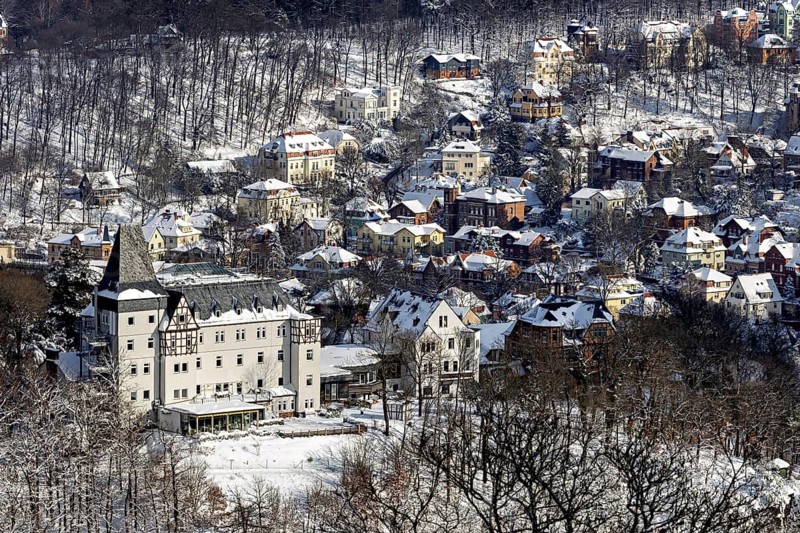 Snowy village with church and snow-covered houses surrounded by wooded hills in a wintry atmosphere, The southern quarter of Eisenach in Thuringia