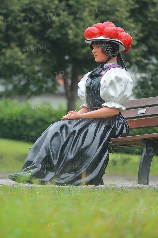 Doll in woman's traditional costume with Bollenhut on bench, Black Forest, Bollenhut, clothing, skirt, tradition, traditional, sitting, park bench, sculpture, flower decoration, Gutach-Black Forest railway, Ortenau, Southern Black Forest, Black Forest, Baden-Württemberg, Germany