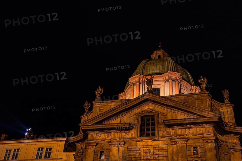 A beautifully lit historical building in Prague, showcasing intricate architectural details and classical sculptures, set against a deep night sky. Perfect blend of history and art