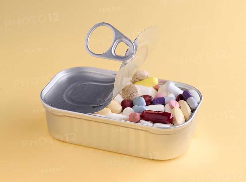 Aluminum can opened to reveal a variety of colorful pills, symbolizing pharmaceuticals and healthcare, isolated on a yellow background