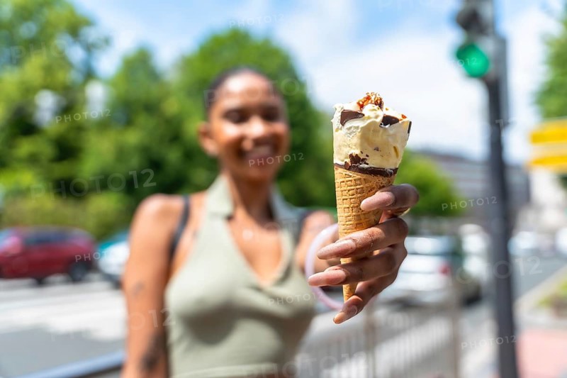Happy woman holding a delicious ice cream cone with chocolate and nuts, cooling down and enjoying a refreshing snack for a sweet moment outdoors on a city street