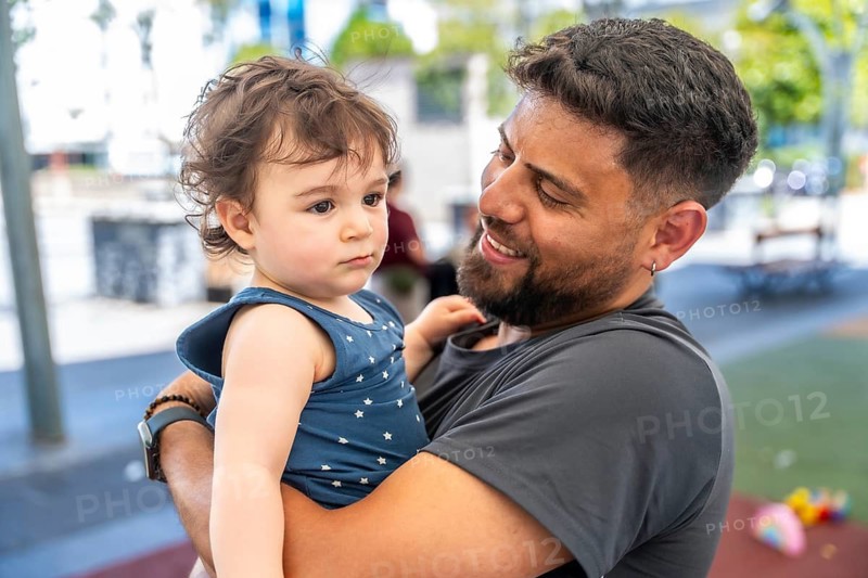 Father holding his young child in an outdoor setting, sharing a tender family moment and expressing joy through their loving connection during childhood