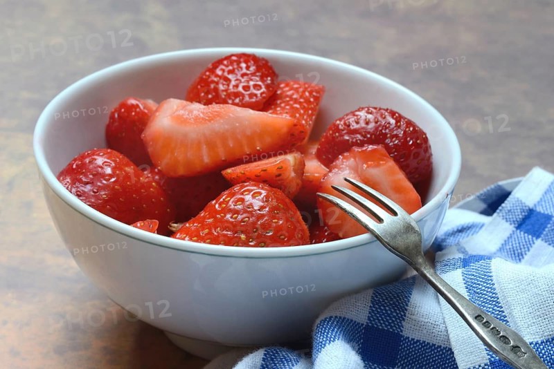 Sliced strawberries in hull with fork, Fragaria