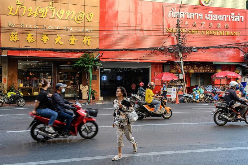Bangkok, Thailand. February 18th 2025. A local woman crosses Yaowarat road busy with motorcycle traffic, Chinatown, Bangkok, Thailand