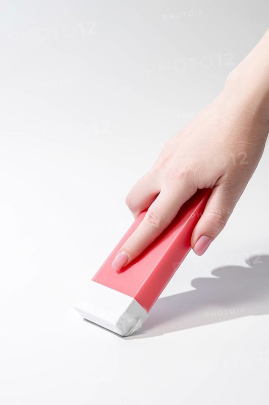 Close up of a hand holding a roll on waxing cartridge designed for easy and effective hair removal. The pink wax cartridge ensures smooth application, offering a professional salon experience