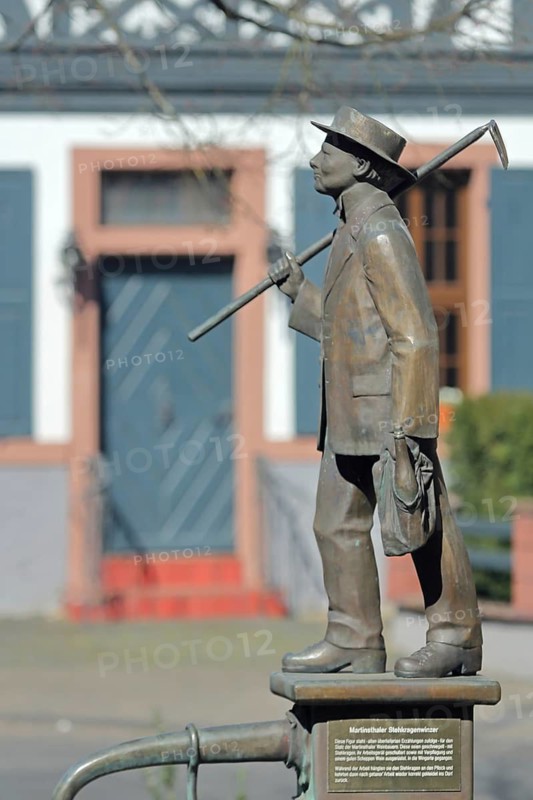 Vintner's fountain with stand-up collar vintner sculpture, vintner, stand-up collar, standing male figure with hoe on his back and bag with wine bottle, garden tool, garden tool, hand, carry, hat, worker, gardener, text, inscription, market square, Martinsthal, Eltville, Rheingau, Taunus, Hesse, Germany