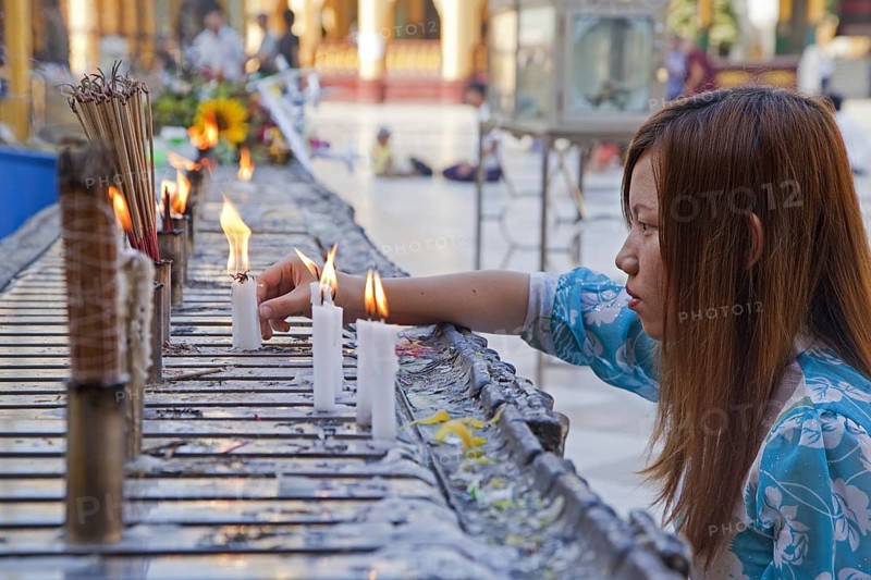 Burmese girl burning candles and incense sticks, joss sticks in the Shwedagon Zedi Daw Pagoda at Yangon, Rangoon, Myanmar, Burma