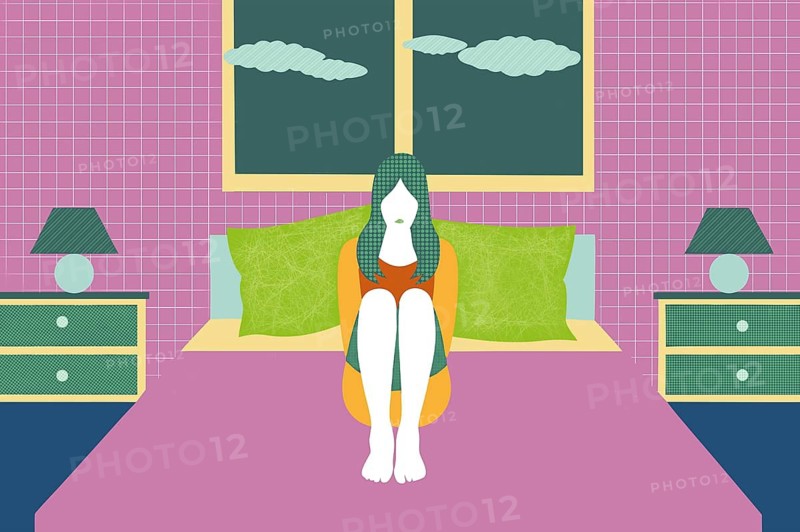 A person is sitting cross-legged on a bed in a vibrant room, surrounded by colorful pillows. This quiet moment suggests feelings of stress and depression while contemplating life