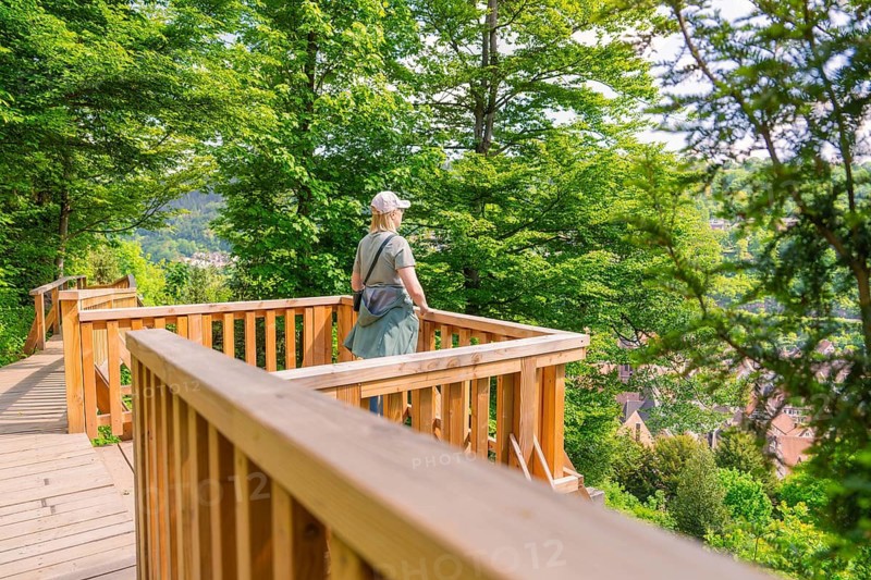 Woman standing on a wooden lookout point with a view of the wooded path, Panorama Holzsteg, Calw, Black Forest, Germany