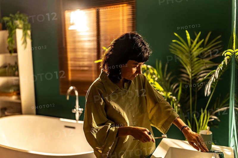 Non binary woman washing the teeth at home in the bathroom