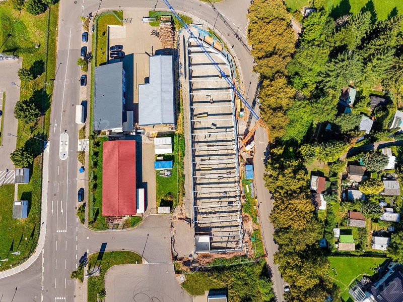 Top view of a construction site surrounded by roads and trees with adjacent residential buildings, Parkhaus Bau, Calw, Germany