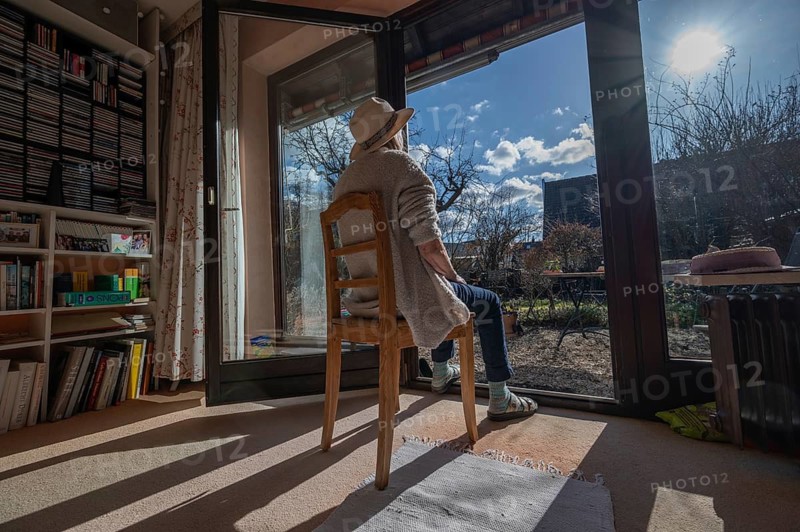 Woman wearing hat sunbathing with patio door open, Bavaria, Germany