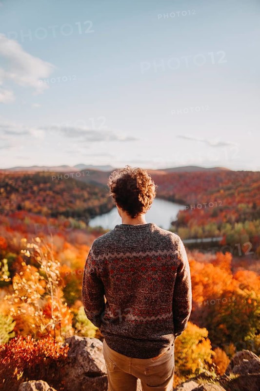 A man enjoys the stunning autumn scenery in Quebec, Canada, as colorful foliage blankets the rolling hills and a river winds through the vibrant landscape
