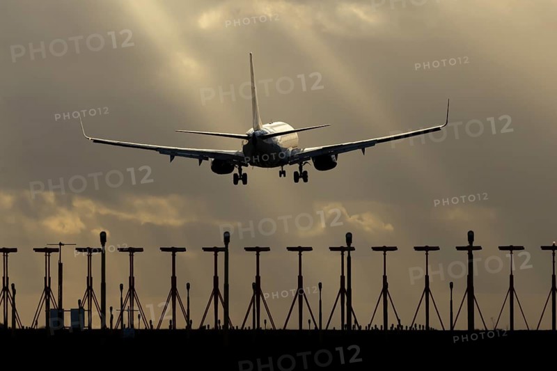 Boeing 737 commercial passenger airliner jet aircraft of Ryanair airways in flight on approach to land over runway lights at sunset at London Stansted airport, Essex, England, United Kingdom