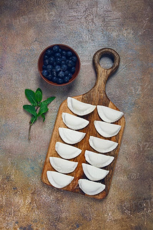 Freshly frozen dumplings with blueberries, raw, top view, no people