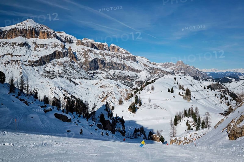 View of a ski resort piste with people skiing in Dolomites in Italy. Ski area Arabba. Arabba, Italy
